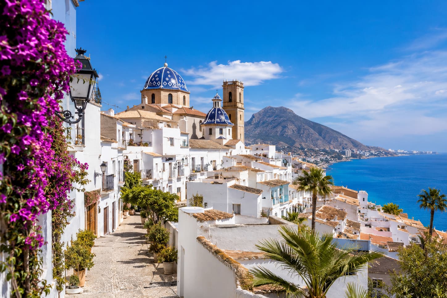 Calle del casco antiguo de Altea con la cúpula azul de la iglesia y la bahía del Mediterráneo al fondo